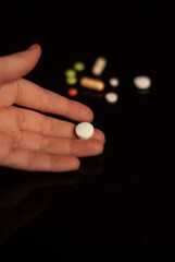 View on pills near hand on the black background