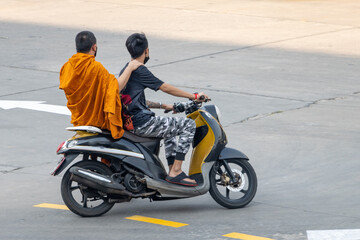 Obraz na płótnie Canvas A man rides a motorcycle with a Buddhist monk, Thailand