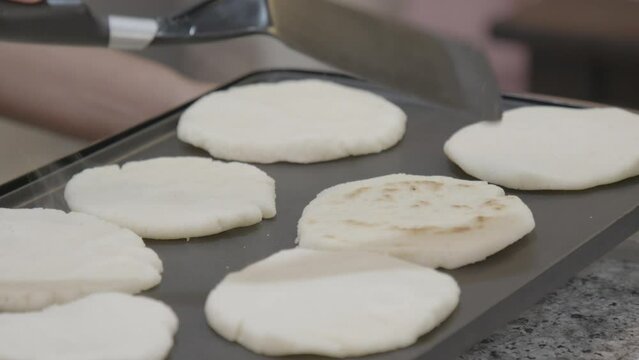 Close-up shot of a woman's hand flipping arepas