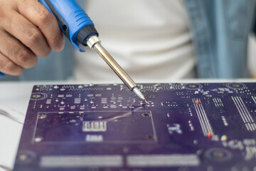 Technician using a soldering iron to repair a circuit board