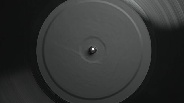 Black vinyl record disc spinning on a turntable player device in flat lay video clip