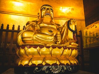 Close up view of a Golden Buddha statue standing in Wat Pho at Bangkok, Thailand