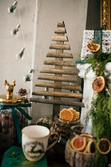 Festive wooden Christmas tree surrounded with holiday decorations