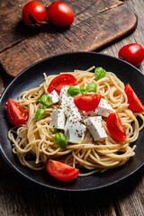 Spaghetti with feta cheese and tomatoes in a plate. Italian pasta
