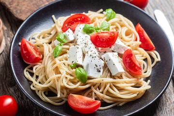 Spaghetti with feta cheese and tomatoes in a plate. Italian pasta