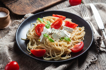 Spaghetti with feta cheese and tomatoes in a plate. Italian pasta