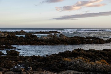 Obraz premium Sandy beach, with rocky outcroppings at the shoreline at sunset in Franzkraal, South Africa