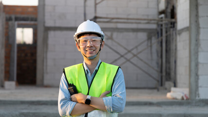 Skilled engineer inspects factory construction and uses a radio to chat with colleagues working on the field, Engineer working outdoors with blueprints and wearing protective safety gear.