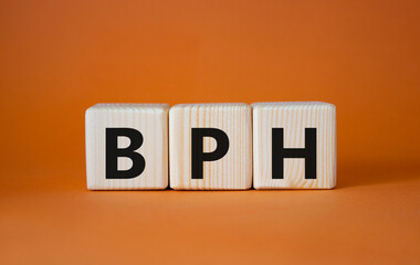 BPH - Benign Prostatic Hyperplasia symbol. Wooden cubes with word BPH. Beautiful orange background. Medical and BPH concept. Copy space.