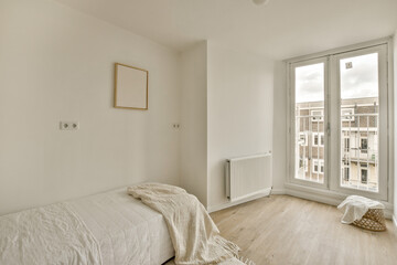 a bedroom with white walls and wood flooring on the floor, there is a large window that looks out onto the street