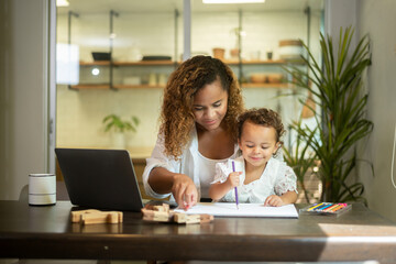 African American mother wearing casual clothes working in her home while daughter playing  or education