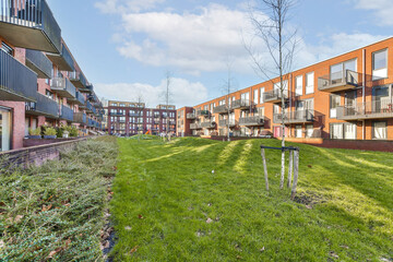Fototapeta na wymiar an apartment complex with green grass and trees in the foreground area on a bright sunny day photo crediton / shutterstocker