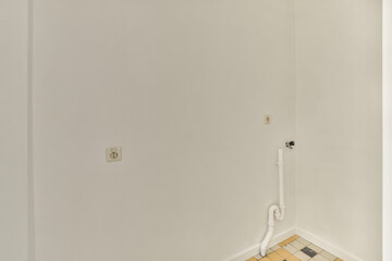 a toilet in the corner of a room with white walls and tile on the floor, there is an open door