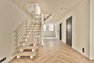 an empty room with stairs and wood flooring in the middle part of the room there is a black door on the right side