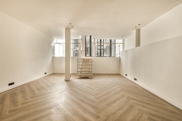 an empty room with wood flooring and white paint on the walls, there is a ladder in the corner