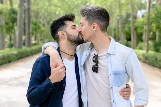 Romantic diverse homosexual guys kissing in green park