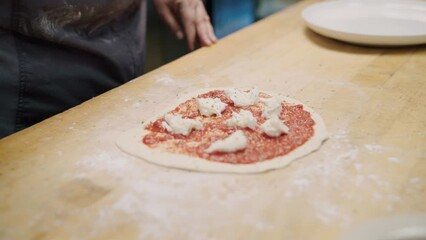 Chef adding ingredients to the pizza dough at the local Italian restaurant