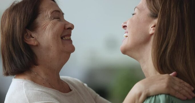 Close up portrait two generation women, older mother, young adult daughter look at each other with love and tenderness, laugh, feel happy, enjoy good family relationship, demonstrating support, care
