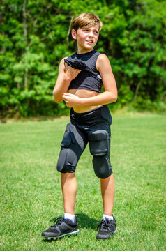 Young sweaty boy athlete lifts up his shirt to cool off during hot football practice 
