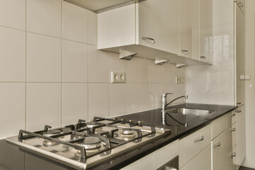 a kitchen with black counter tops and white tiles on the wall behind it is an oven, sink and dishwasher