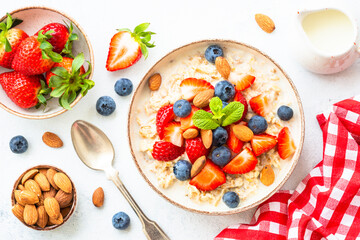 Oatmeal porrige with fresh berries and nuts. Healthy breakfast, top view.