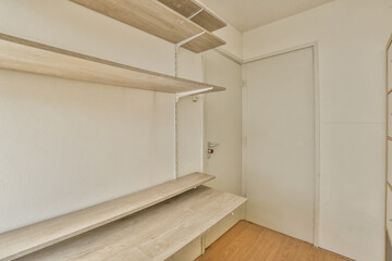 a room with white walls and wooden shelves on the wall, there is a door in the corner to the right