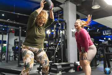 Two plus-size women workout and exercise with medicine ball at the gym. They're determined to achieve their goals and inspire others along the way. - obrazy, fototapety, plakaty