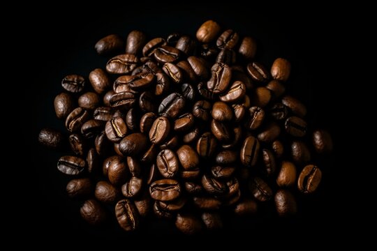 a pile of coffee beans with a black background and a black border around the beans is a picture of coffee beans and a coffee bean. generative ai