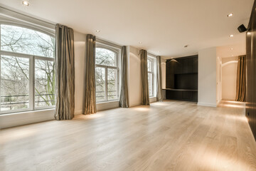 an empty living room with wood flooring and large windows looking out onto the trees that line the landscape outside