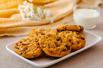 Chocolate chip cookies on white plate and glass of milk