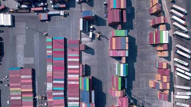 Top down aerial view of reach-stacker driving at outdoor cargo container warehouse. Container handler at cargo container warehouse. 