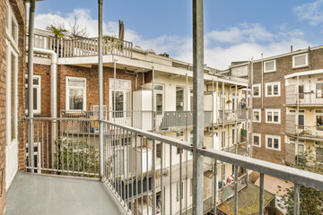 Fototapeta premium a balcony with some buildings in the background and a blue sky above it, taken from an apartment balcony railing