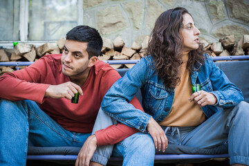 Very drunk couple, a boy and a girl, drink a strong alcoholic drink from small glasses. Bad social unhappy atmosphere