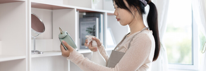 Young housewife holding a spray bottle to clean things in the living room, Big cleaning, Housework, Daily routine ,Removes germs and dirt and deep stains, Spray alcohol, Clean up.