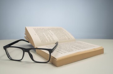 Closeup of reading glasses on an open book on a white surface
