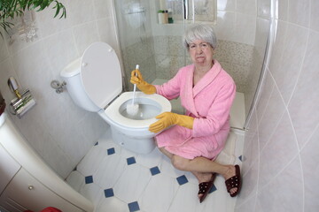 Grossed out senior woman cleaning the toilet  - obrazy, fototapety, plakaty