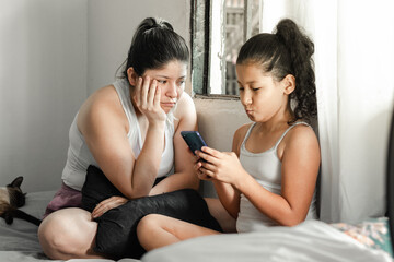 young mother very bored with her young daughter, because she does not let go of her cell phone.