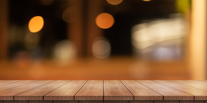 Empty wooden table top with lights bokeh on blur restaurant background.