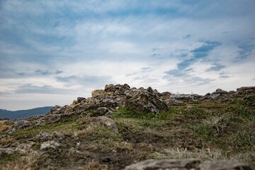Fototapeta na wymiar Landscape of rocky hills covered in the grass under a blue cloudy sky
