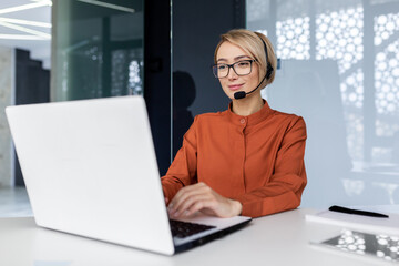 Successful businesswoman with video call headset working inside modern office, online customer...