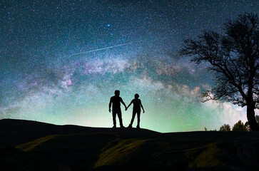 Fantasy landscape, couple lovers silhouette standing on the hill, on the milky way galaxy...