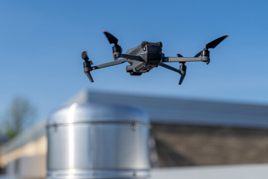 Drone being used to perform an aerial inspecting of HVAC RTU equipment on a commercial roof.