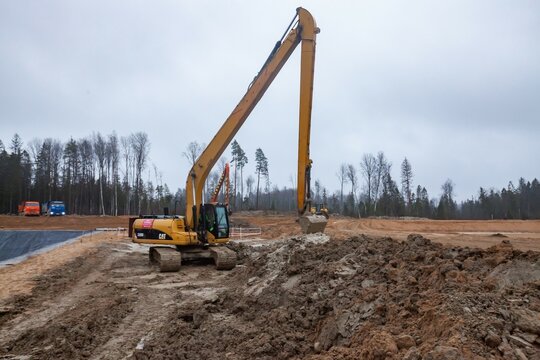 Ust-Luga, Leningrad oblast, Russia - November 16, 2021: Caterpillar excavator with long boom dig pit