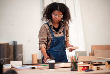 Small business owner young black female carpenter working a wood work in carpentry workshop. Young woman handcrafting and design chair for minimal home furniture.