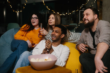 A group of friends eat snacks and drink beer while watching TV.