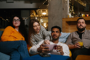A group of friends eat snacks and drink beer while watching TV.