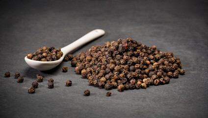 Dry ground black pepper corn spices for recipes. Spoon and a pile of hot powder pepper. Ground spice