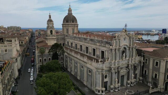 Beautiful drone view 4K video of Catania historical center on Duomo square in Sicily, Italy with the cathedral of St. Agatha and the harbour in the background
