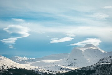 Fototapeta na wymiar Majestic mountain range blanketed in freshly fallen snow under a blue sky with clouds.