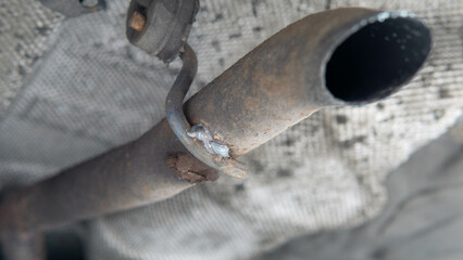 New exhaust pipe bracket repaired after soldering fracture, view of car chassis
